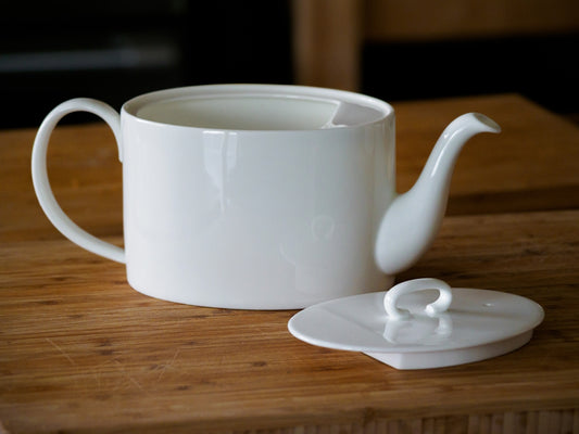 a white teapot sitting on top of a wooden table