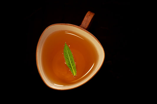 A cup of tea with a green leaf.