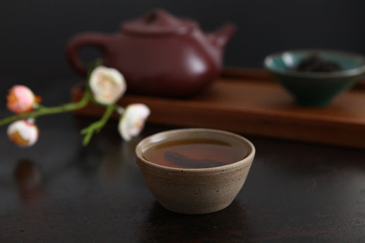 a cup of tea next to a teapot and a flower