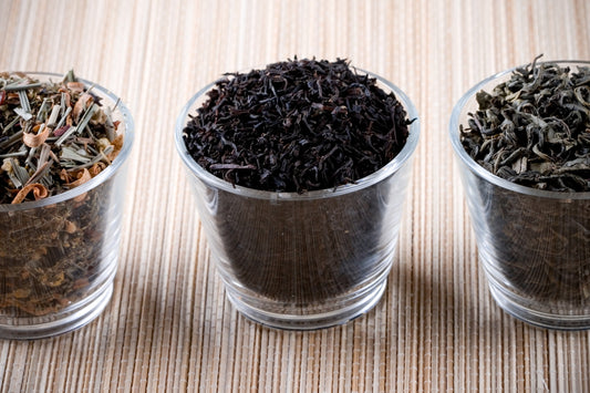 Three glass cups filled with different types of tea
