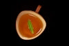 A cup of tea with a green leaf.