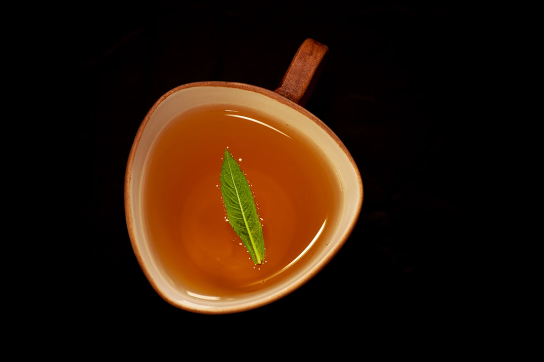 A cup of tea with a green leaf.
