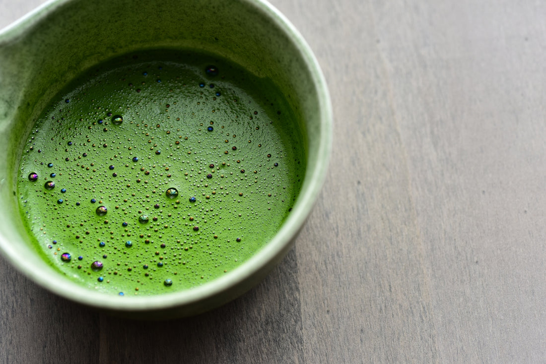 A cup of frothy, vibrant green matcha tea.